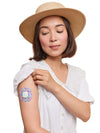 Woman wearing a Simplera Sensor Patch on her arm, showing colorful design and secure fit.