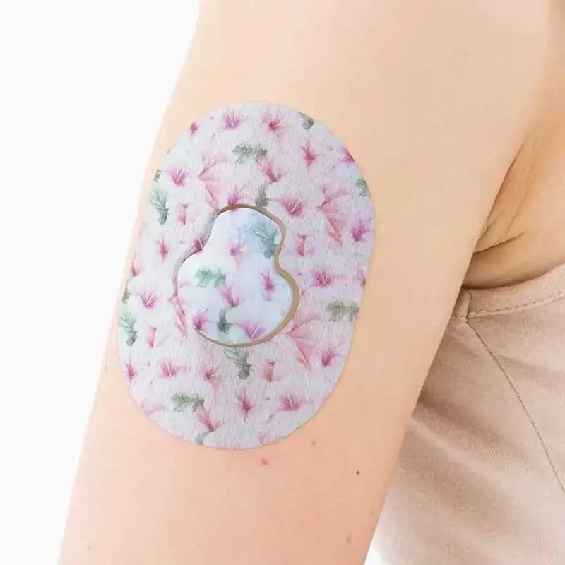 Guardian Enlite Sensor Patches worn on arm, featuring a pink and green floral design for daily use and protection. Bild